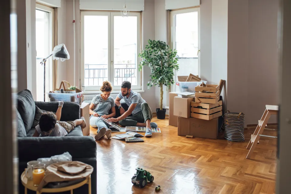 Man, woman, and child in apartment with moving boxes and crates.